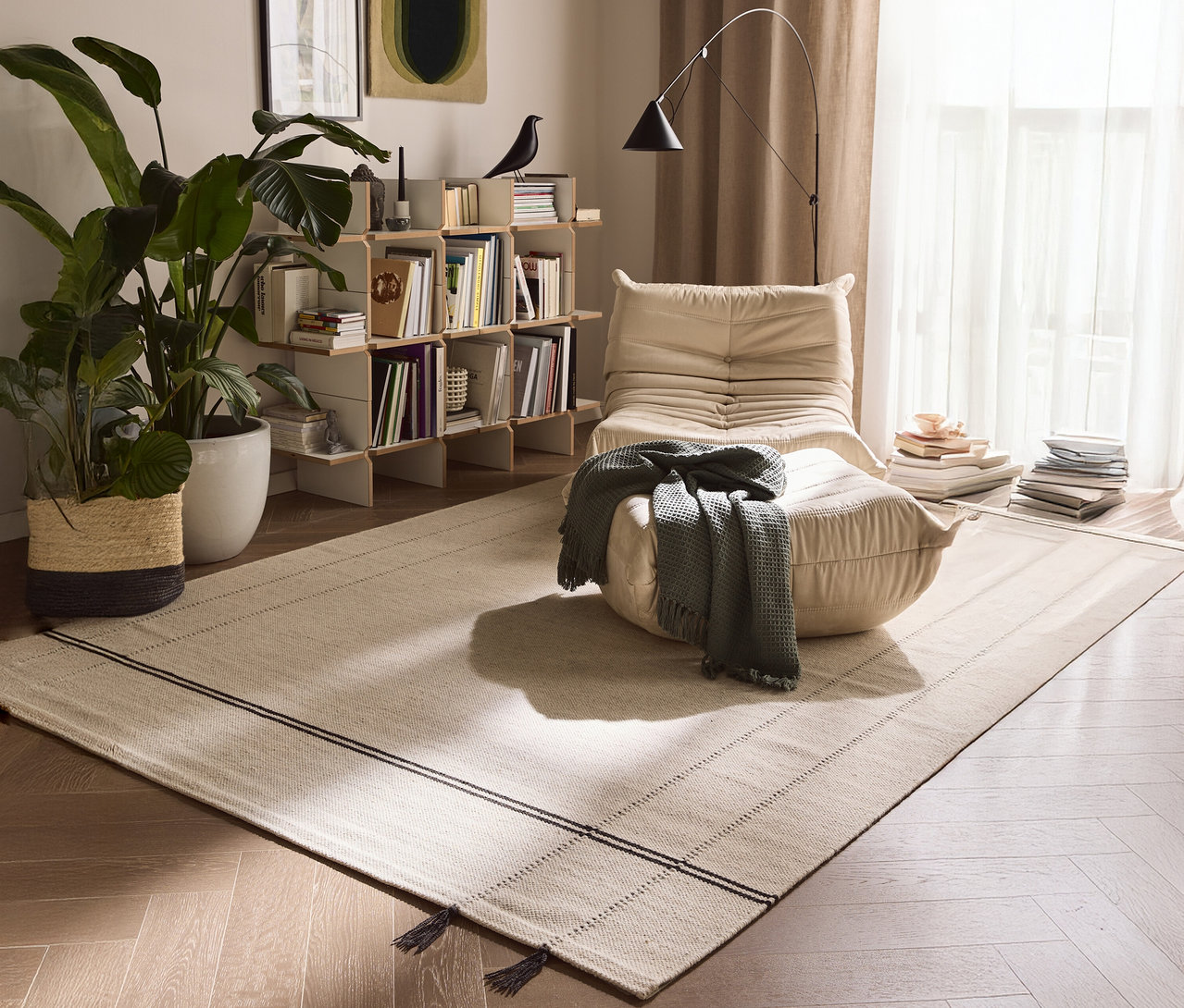 Ein beiger Sessel mit einer grauen Decke steht auf einem beigen Teppich in einem Wohnzimmer.