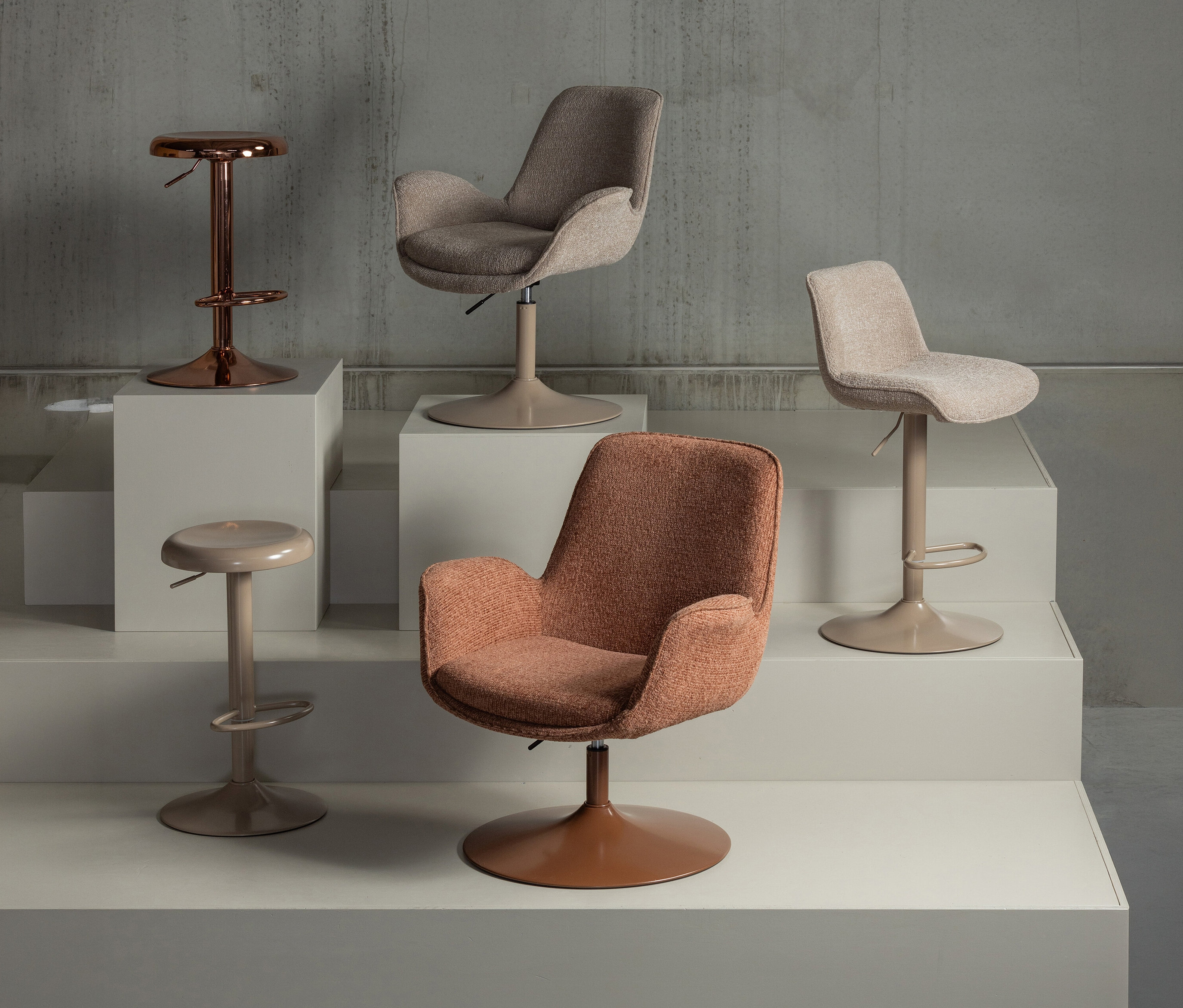 Vier Stühle stehen auf weißen Podesten, darunter ein kupferfarbener WOOOD »Marten« Barhocker.