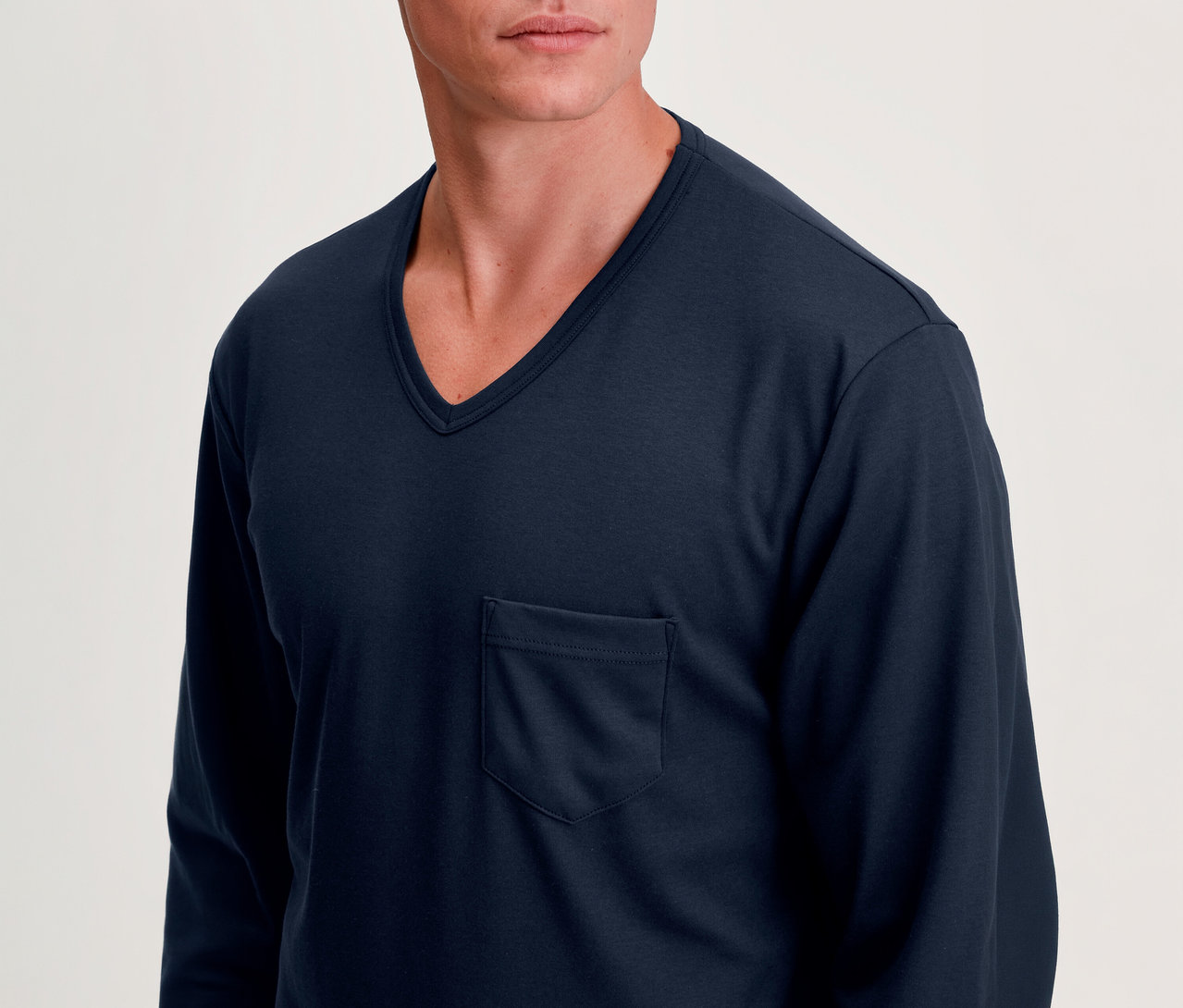 Mann trägt ein dunkelblaues Langarm-V-Ausschnitt-Shirt mit Brusttasche.