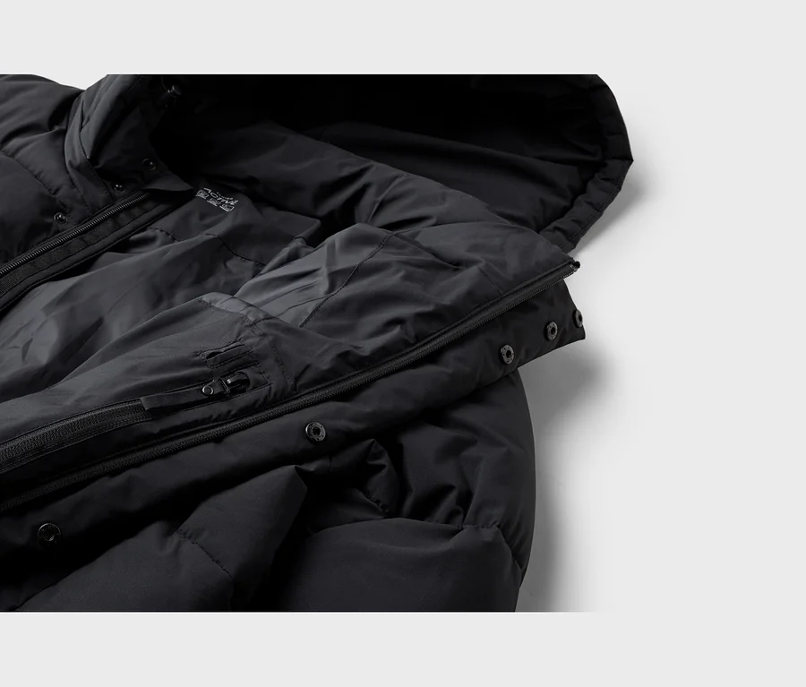 Nahaufnahme einer schwarzen Steppjacke mit Kapuze, Reißverschlüssen und Druckknöpfen.