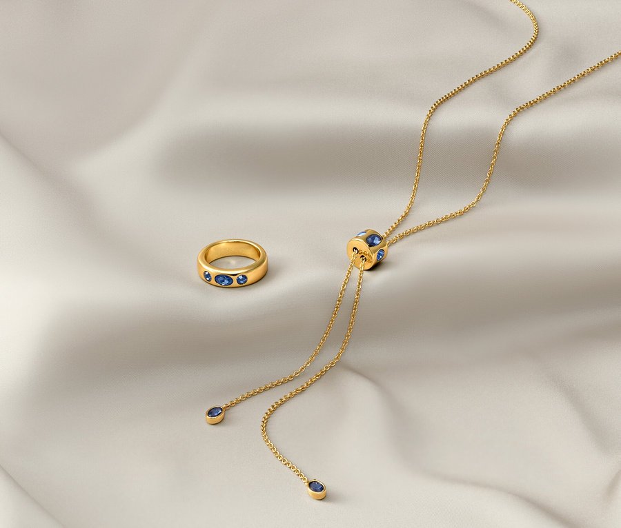 Auf einem weißen Tuch liegen eine goldene Kette »Iconic« und ein goldener Ring »Iconic«.