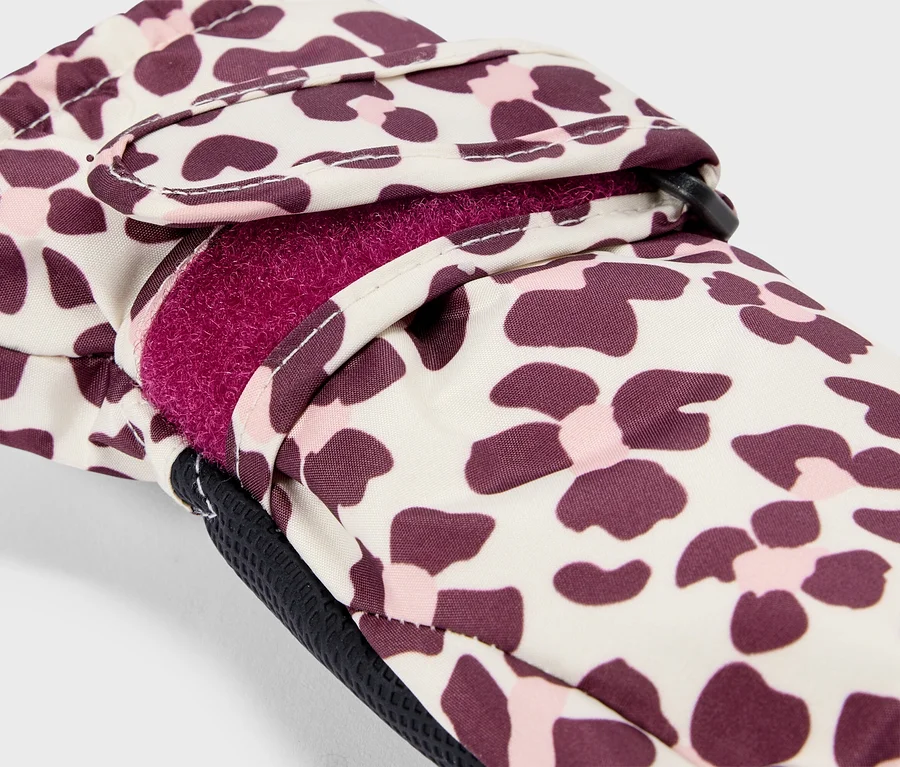 Nahaufnahme eines Handschuhs mit cremefarbenem Hintergrund und leopardenähnlichem Muster in Dunkelviolett und Hellrosa. Das Innere des Handschuhs ist mit leuchtend pinkem Fleece gefüttert, und ein Klettverschluss ist sichtbar.