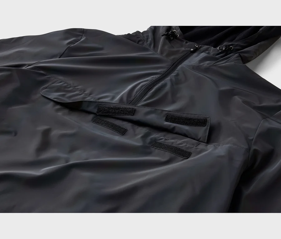 Nahaufnahme einer schwarzen Anorakjacke mit Halbreißverschluss, Kapuze mit Kordelzügen und großer Pattentasche mit Klettverschlüssen.