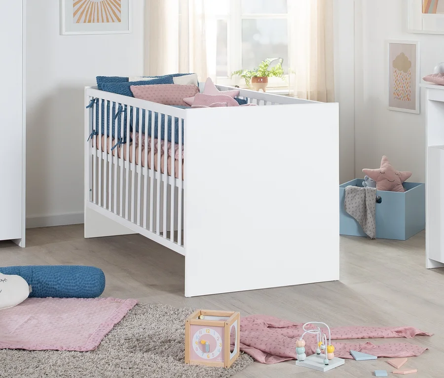 Weißes Roba Lilo Kinderbett mit blauen und rosa Kissen und einer rosa Sternen-Decke in einem hellen Kinderzimmer. Auf dem Teppich liegen Spielzeug und eine rosa Decke.