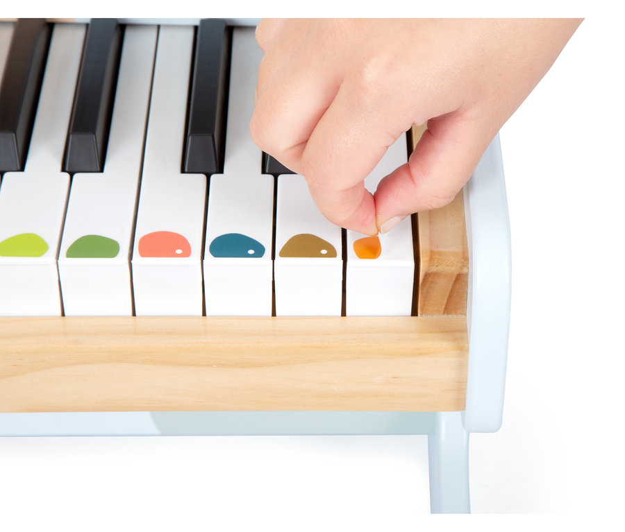 Eine Hand klebt einen orangefarbenen Aufkleber auf eine weiße Taste des small foot Klaviers »Groovy Beats«.