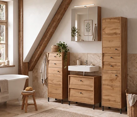 Rustikales Badezimmer mit freistehender Badewanne und drei Eichenholzmöbeln. Links neben dem weißen Waschbecken steht ein Highboard »Cottage«, darunter ein Waschbeckenunterschrank »Cottage« und rechts ein Hochschrank »Cottage«.