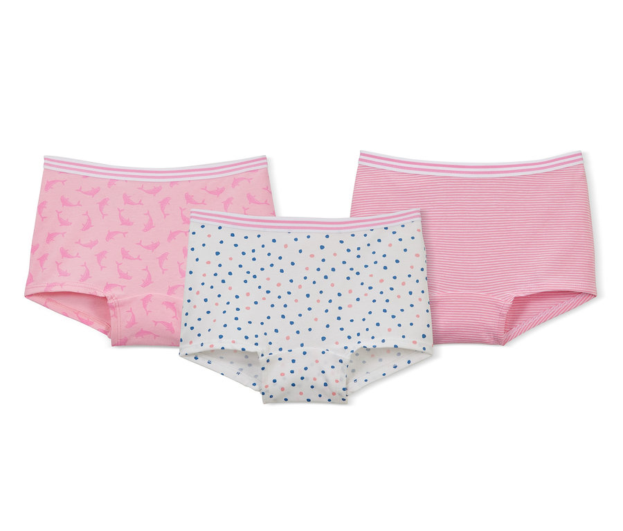 Drei Mädchen-Pantys liegen auf einem weißen Hintergrund: eine rosa mit Delfinen, eine weiße mit bunten Punkten und eine rosa gestreifte.