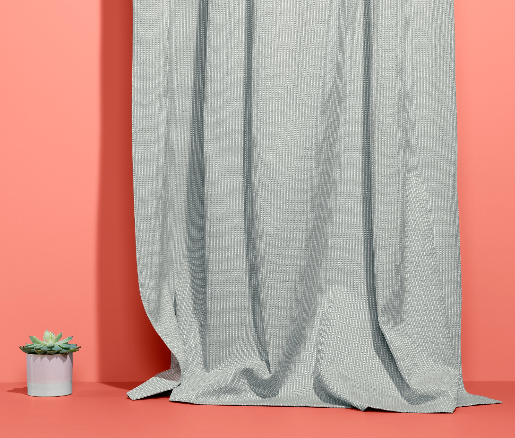 Graue 2 Vorhangschals hängen neben einer kleinen Topfpflanze.