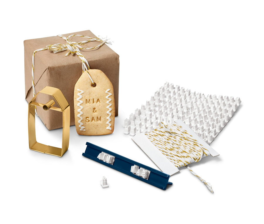 Ein braunes, verpacktes Geschenk, ein Keksstempel-Set, ein Keksausstecher und eine Schnur.