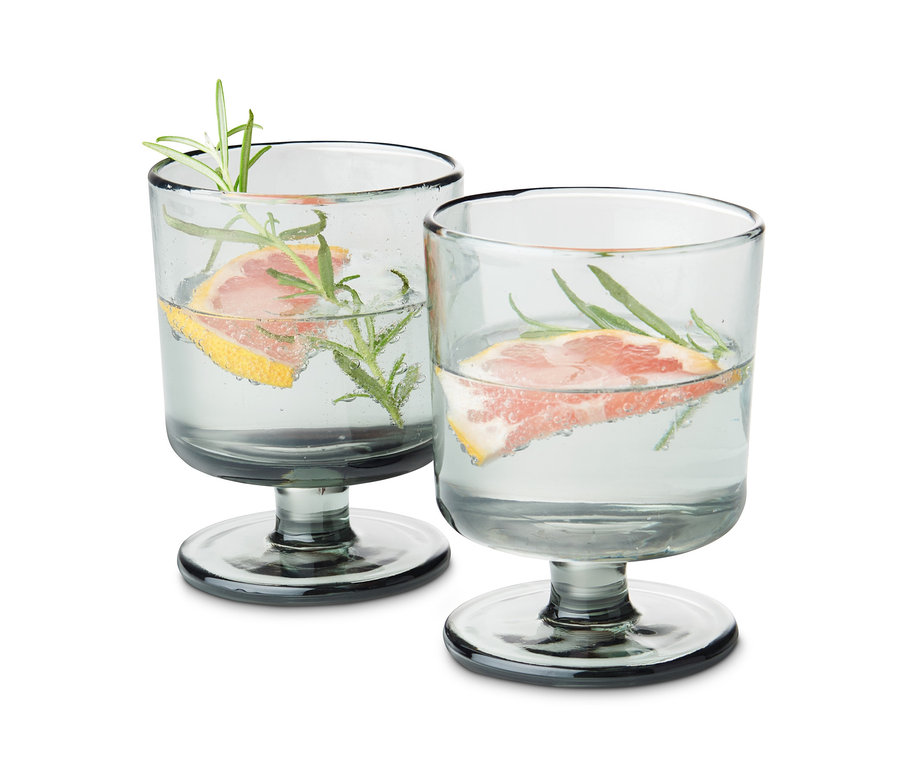 Zwei Gläser mit Fuß, gefüllt mit Wasser, einer Grapefruitscheibe und Rosmarin.