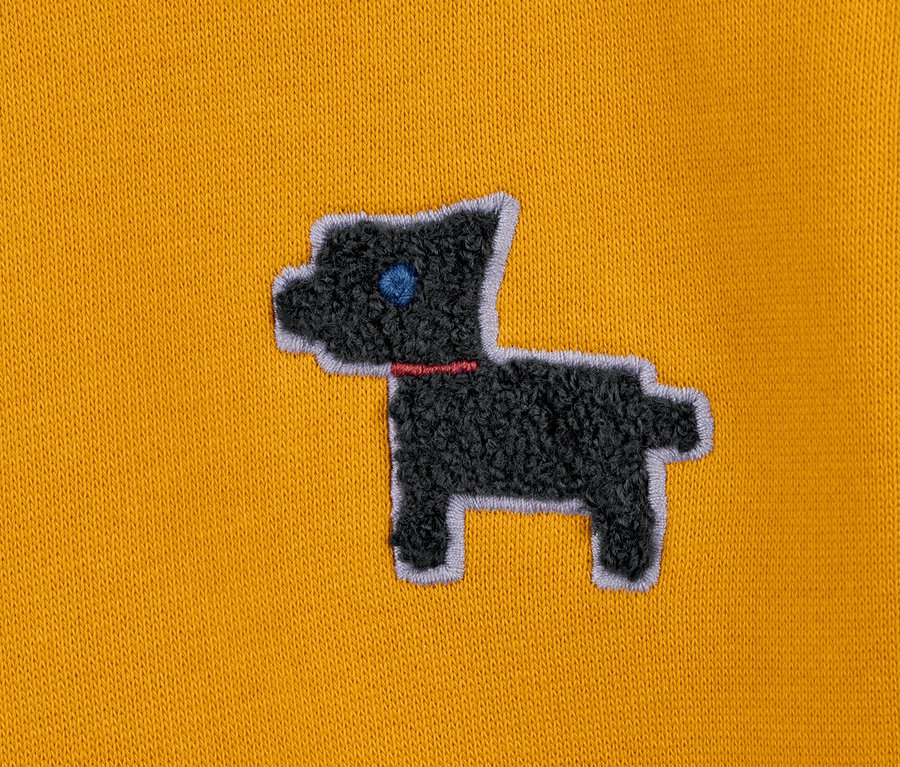 Detailansicht eines gelben Sweatkleids mit Applikation eines schwarzen Hundes.