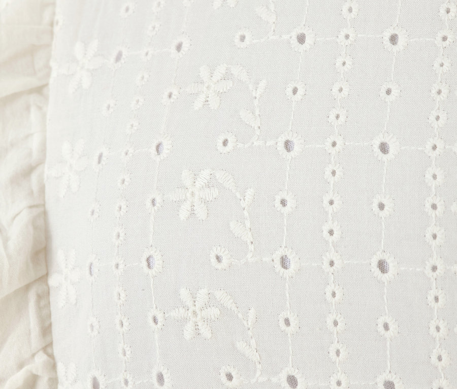 Detailansicht eines weißen Sweatshirts mit Lochstickerei.