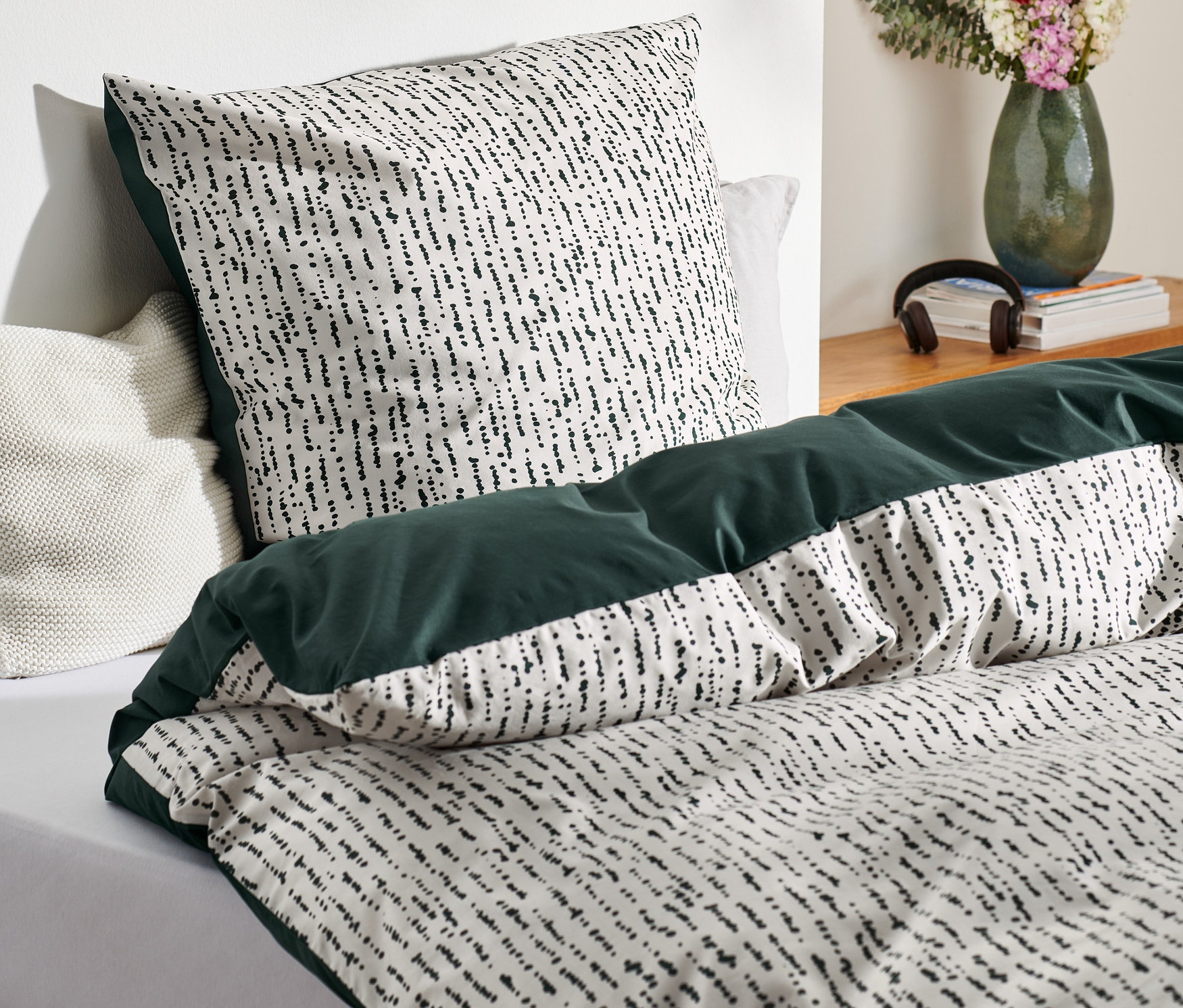 Detailansicht von Premium-Baumwoll-Bettwäsche mit schwarzem Muster auf weißem Grund und dunkelgrüner Bordüre.