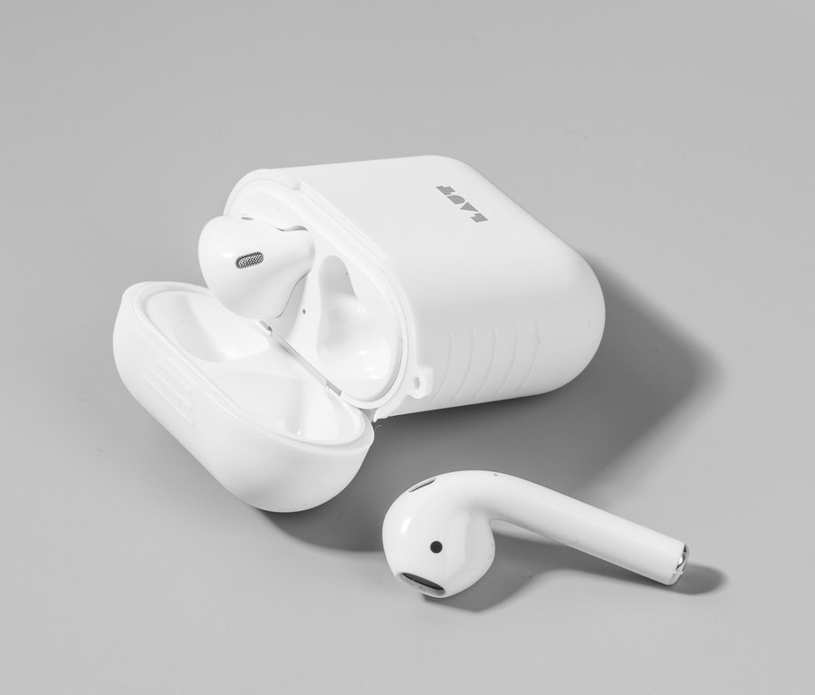 Weißes LAUT Case für AirPods Serie 1 und 2 »POD«, mit einem Ohrhörer drinnen und einem daneben auf grauem Hintergrund.