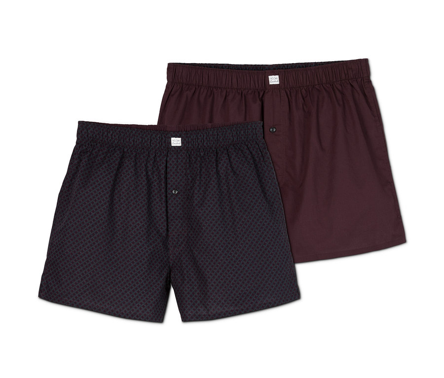 Zwei Webboxershorts, eine dunkelblau gemustert, die andere bordeauxrot.