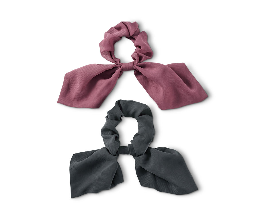 Zwei Haargummis »Scrunchies« mit Schleife liegen auf weißem Hintergrund.