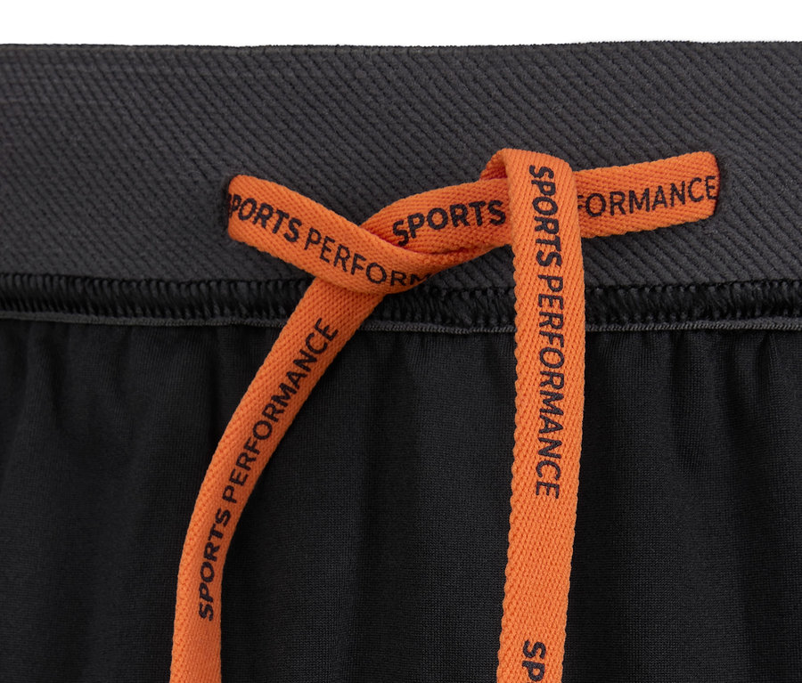 Detailaufnahme einer Sportshorts mit orangefarbenem Kordelzug.
