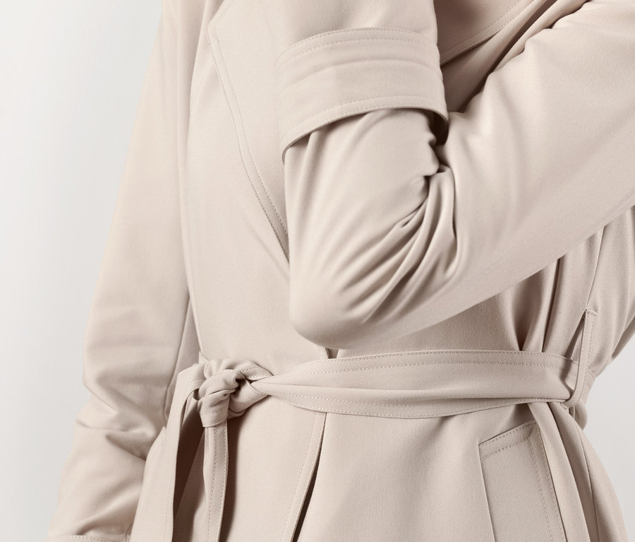 Frau posiert in beigem Trenchcoat.