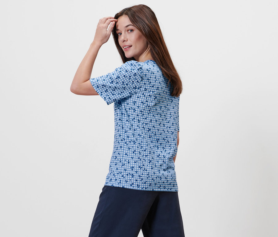 Frau posiert in blauem Blusenshirt mit Alloverprint.