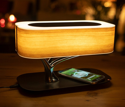 Induktive Ladestation mit BT-Lautsprecher und Lampe auf einem Tisch.