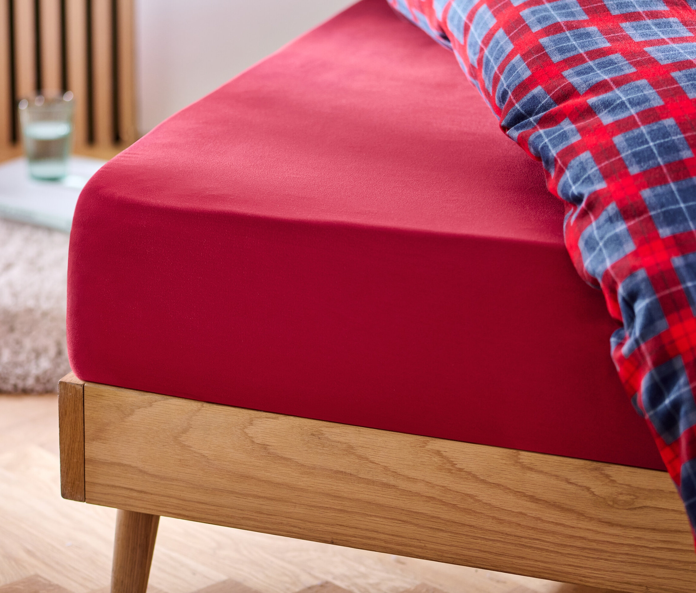 Rotes Microfaser-Flanell-Spannbettlaken auf einem Bett.