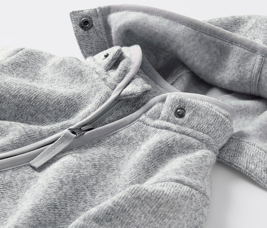 Detailansicht eines Baby-Strickfleece-Overalls mit Reißverschluss und Druckknöpfen.