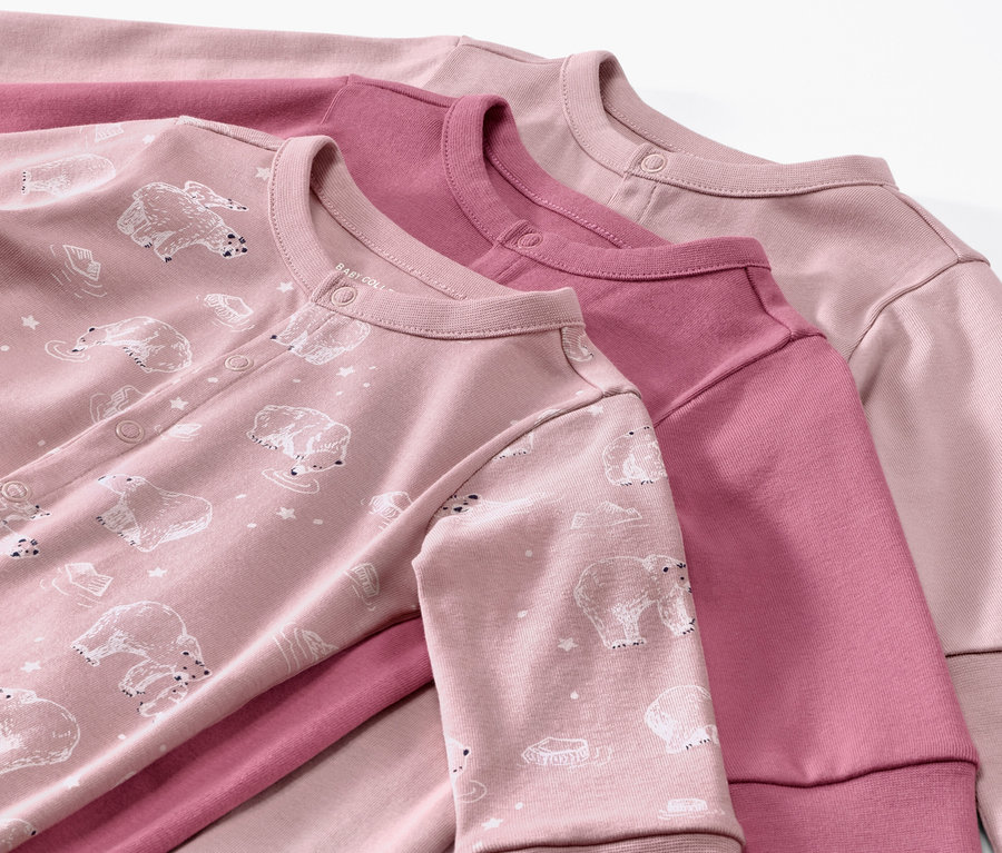 Drei rosa Baby-Pyjamas liegen übereinander.