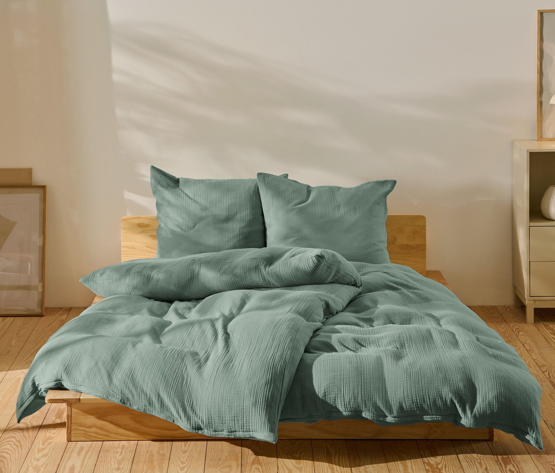 Grüne Musselin-Bettwäsche in Normalgröße und Übergröße auf einem Bett.