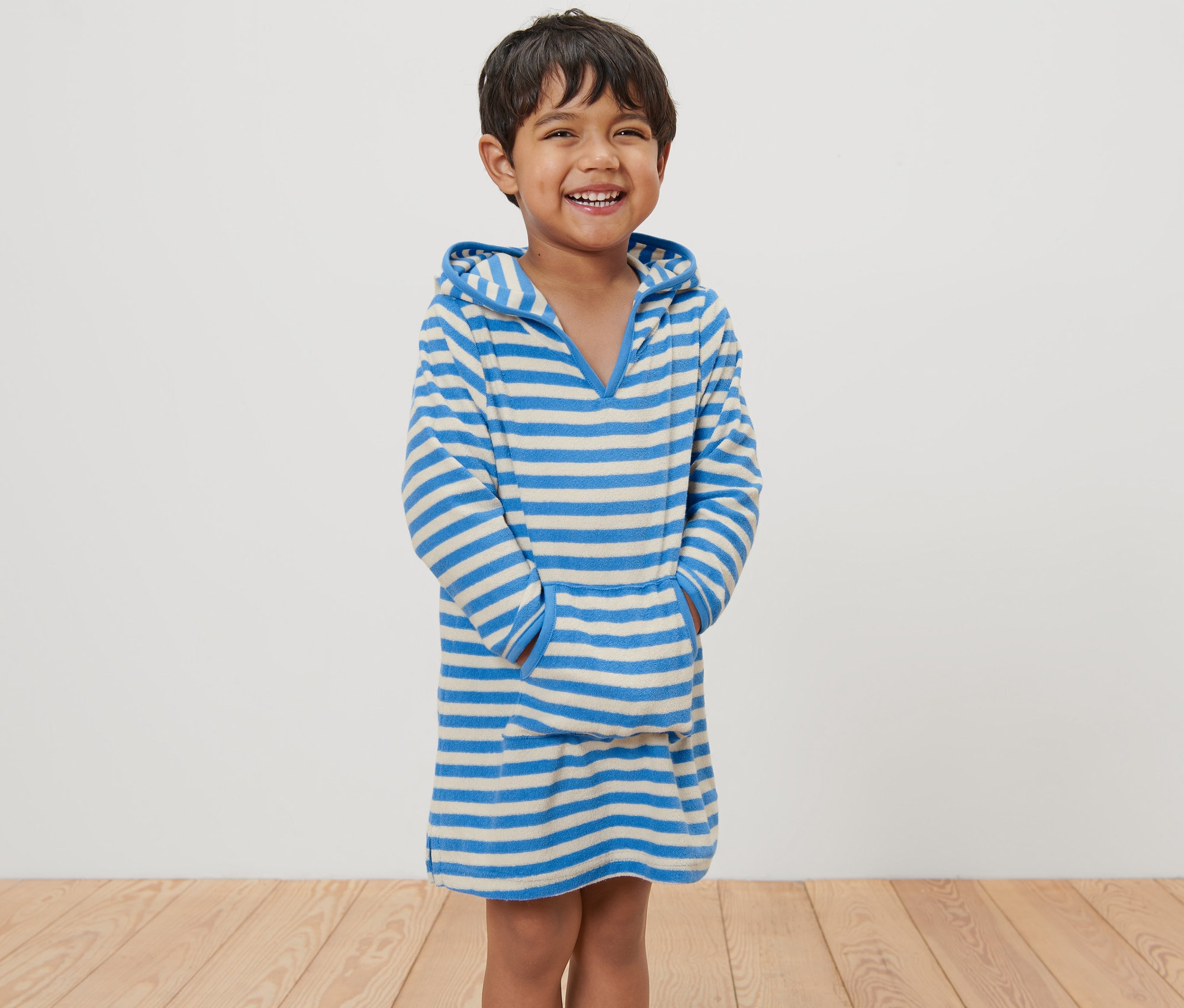 Lächelnder Junge posiert in einem gestreiften Kinder-Frottierponcho.