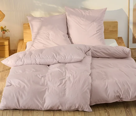Rosafarbene Baumwollsatin-Bettwäsche in Normalgröße und Übergröße auf einem Bett.