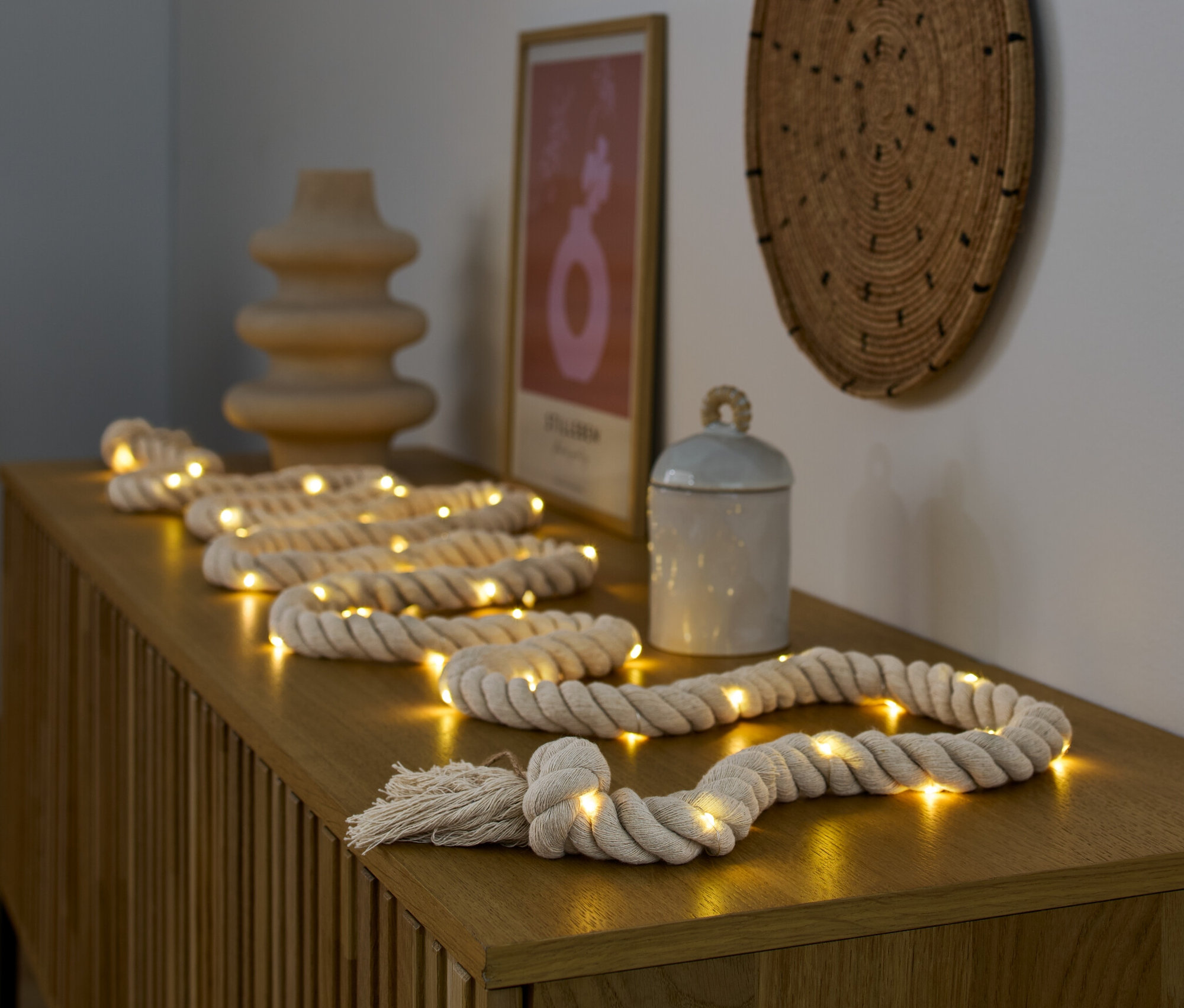 LED-Lichterkette »Tau« liegt auf einer Holzkommode neben einer Vase und einer Dose.