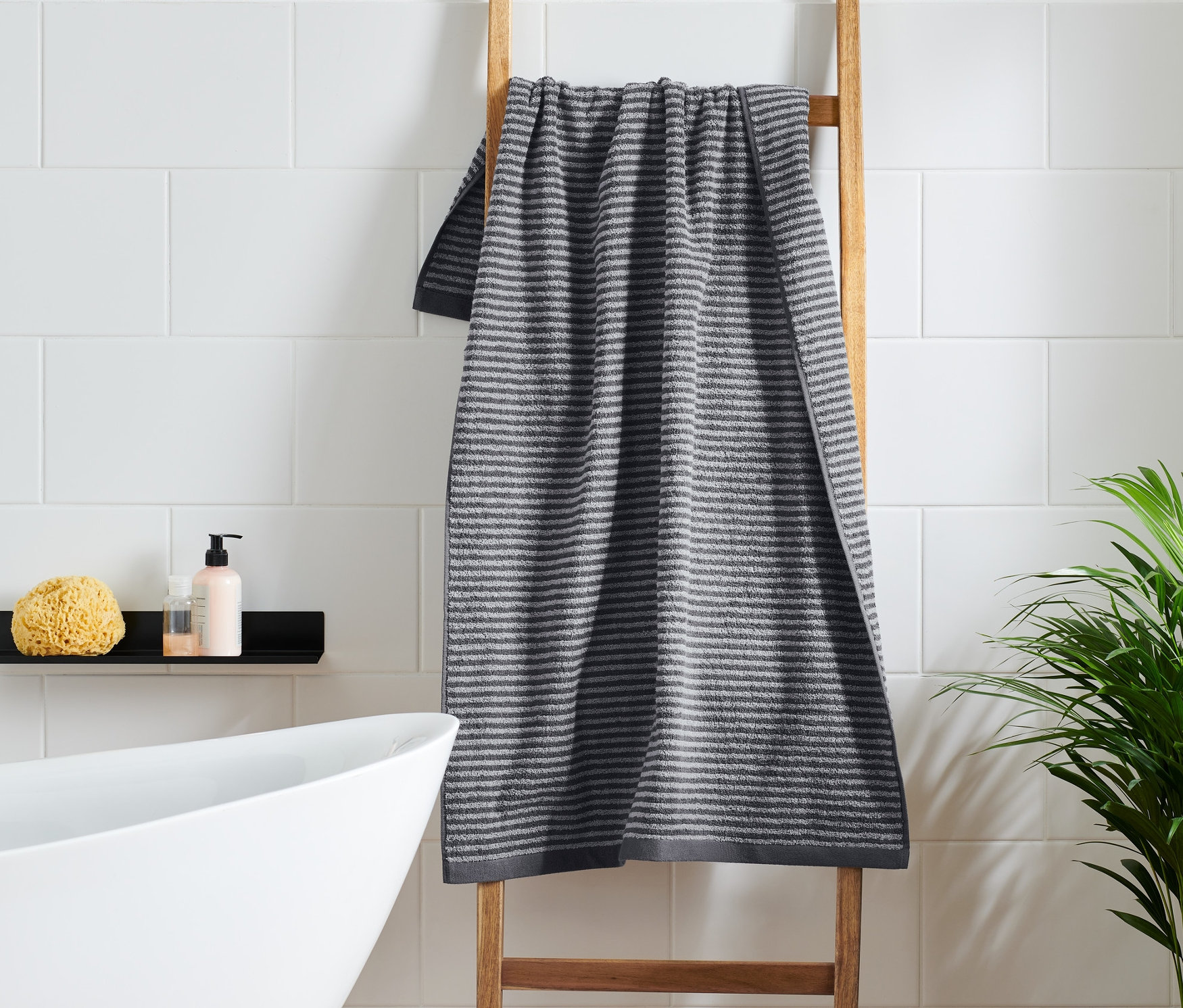 Anthrazitfarbenes Badetuch hängt auf einer Holzleiter im Badezimmer.