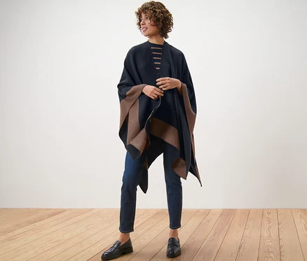 Eine Frau steht auf einem Holzboden und trägt einen Wende-Poncho.