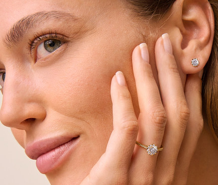 Frau mit 585 Gold Ring Diamanten am Finger und 585 Gold Ohrstecker Diamanten im Ohr.
