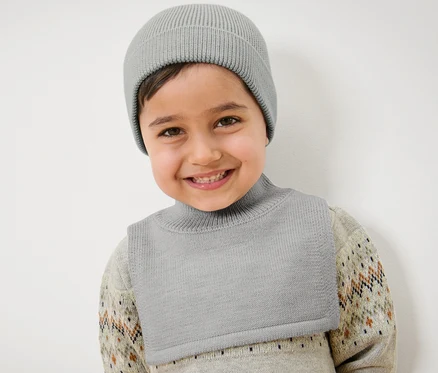Lächelndes Kind trägt eine graue Kinder-Woll-Strickmütze.
