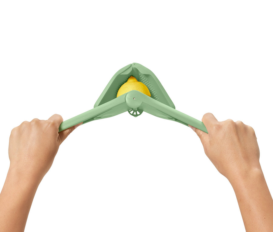 Zwei Hände pressen eine grüne Platzspar-Zitruspresse mit einer Zitrone darin.