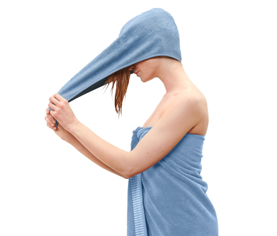 Frau wickelt ein blaues Turban-Handtuch um ihren Kopf.