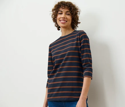 Frau trägt ein gestreiftes Shirt mit 3/4-Arm und Jeans.