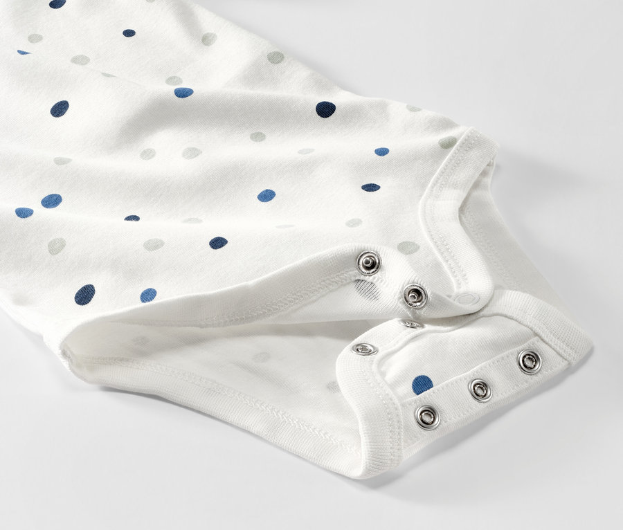 Detailansicht von 5 Baby-Bodys mit Mitwachsfunktion, mit blauen und grauen Punkten.