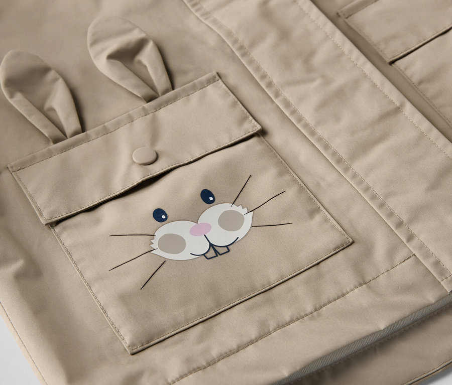 Detailansicht einer braunen Kinder-Regenjacke mit Hasengesicht-Tasche.