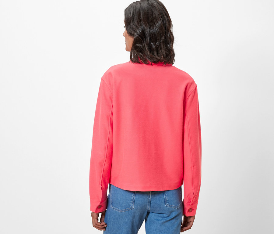 Rückansicht einer Frau in Jerseyjacke und Jeans.