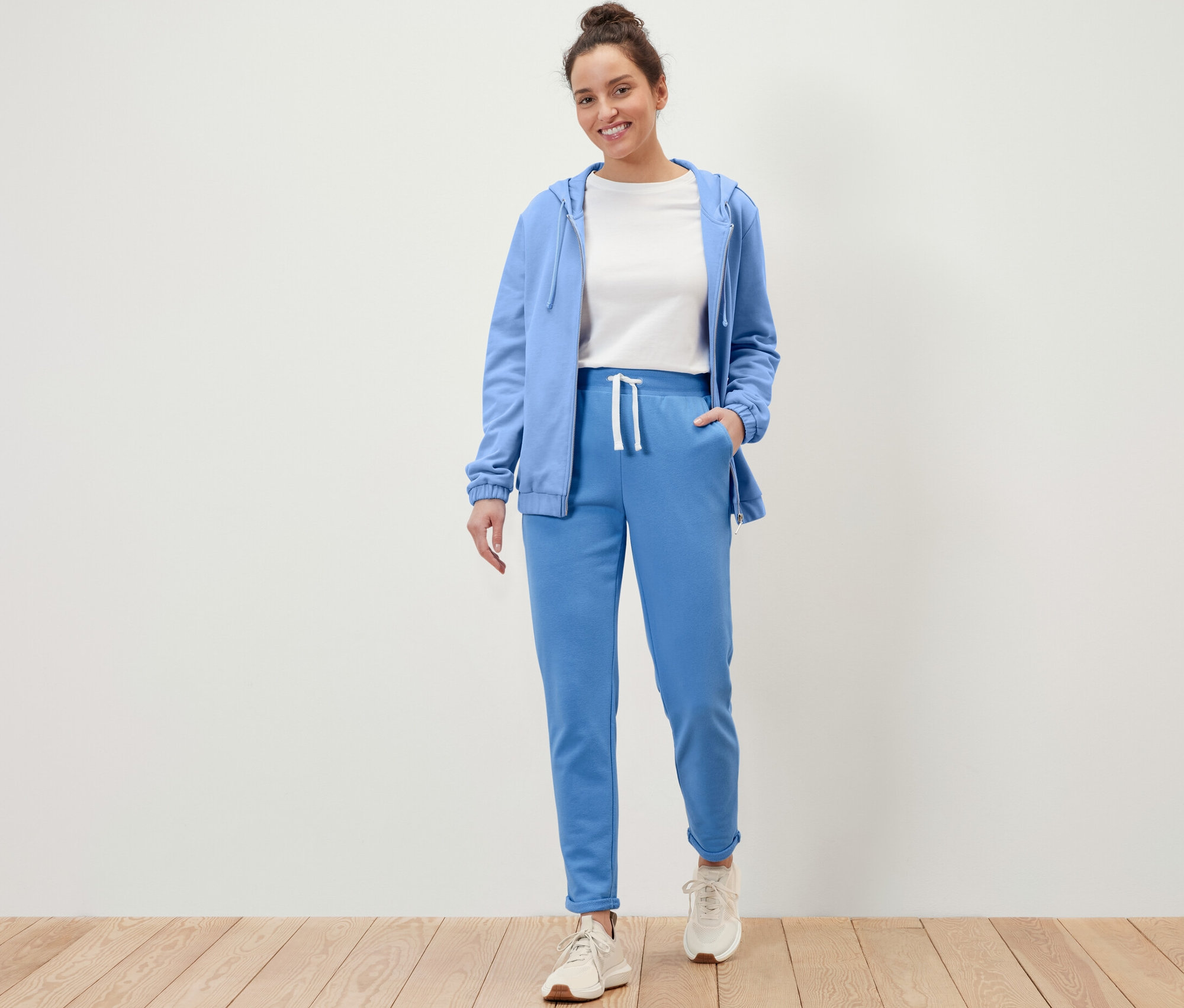 Frau steht und trägt hellblaue Sweatpants und eine Jacke.