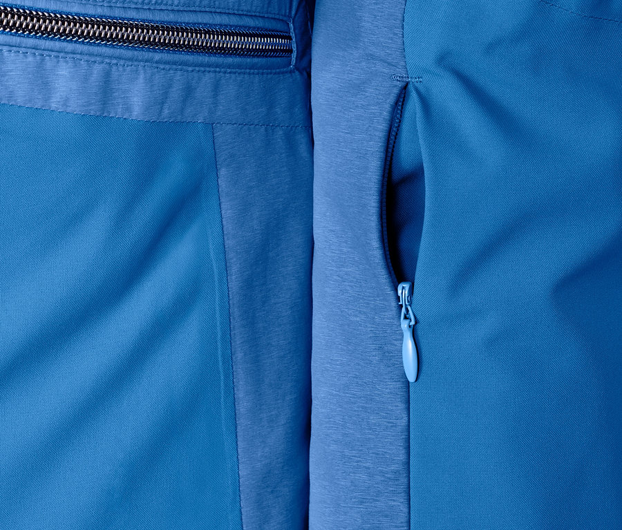 Detailaufnahme einer blauen Softshell-Skijacke mit Reissverschlüssen.