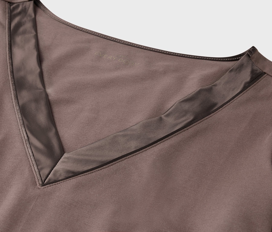 Detailansicht eines braunen Oberteils mit V-Ausschnitt und Satineinfassung.