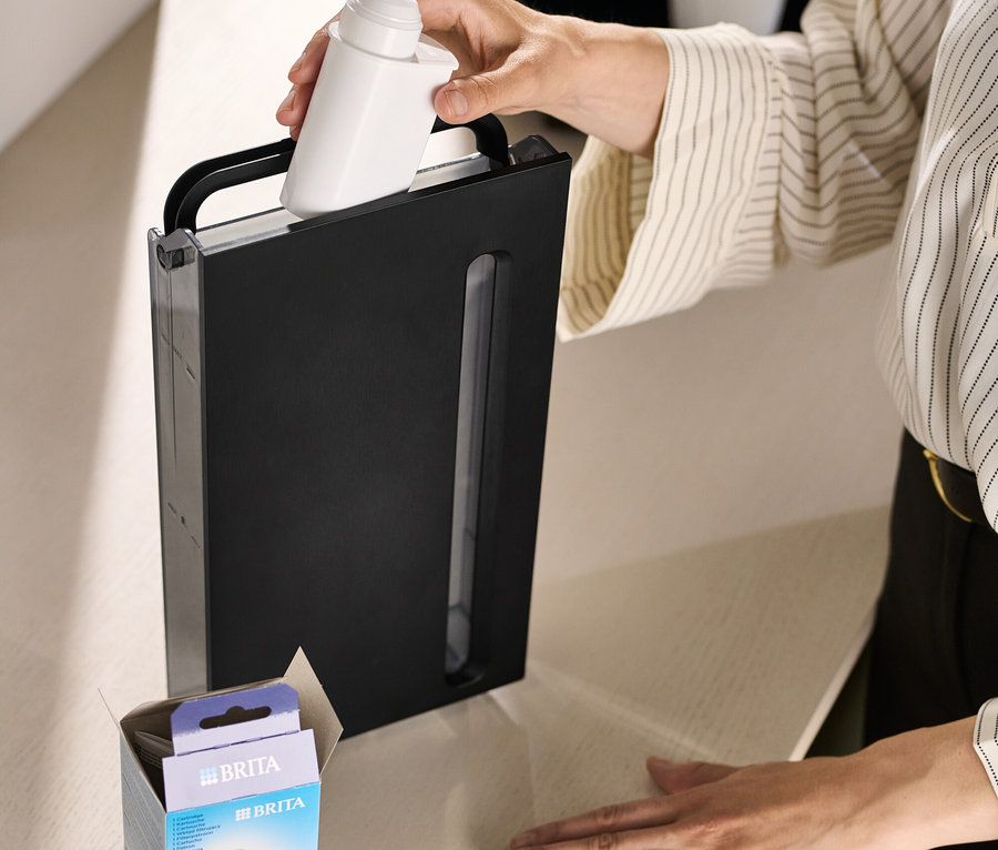 Frau setzt Brita AquaAroma Crema Filter in schwarzen Wasserbehälter ein.