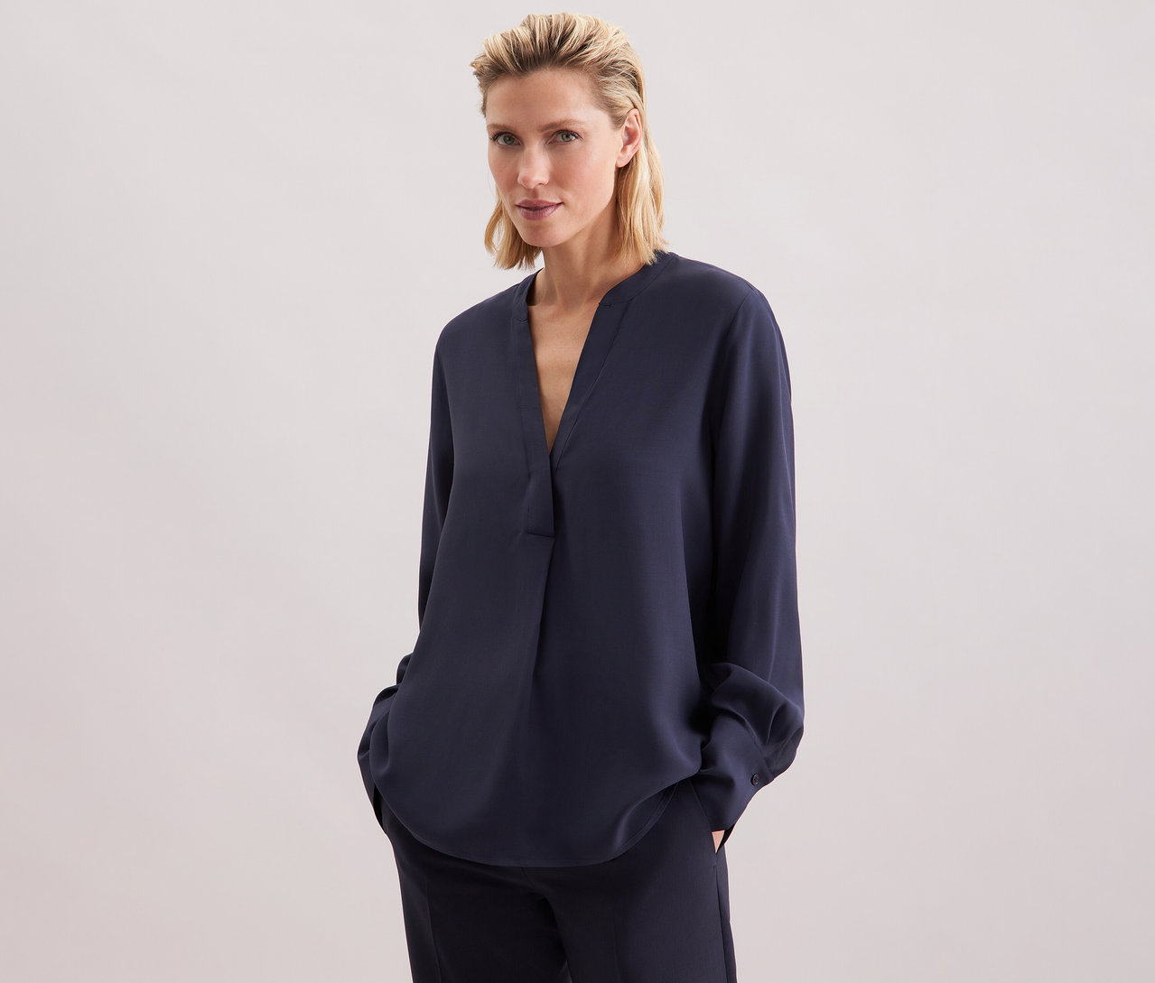 Frau trägt eine marineblaue Seidensticker Tunika aus Viskose und eine Hose.