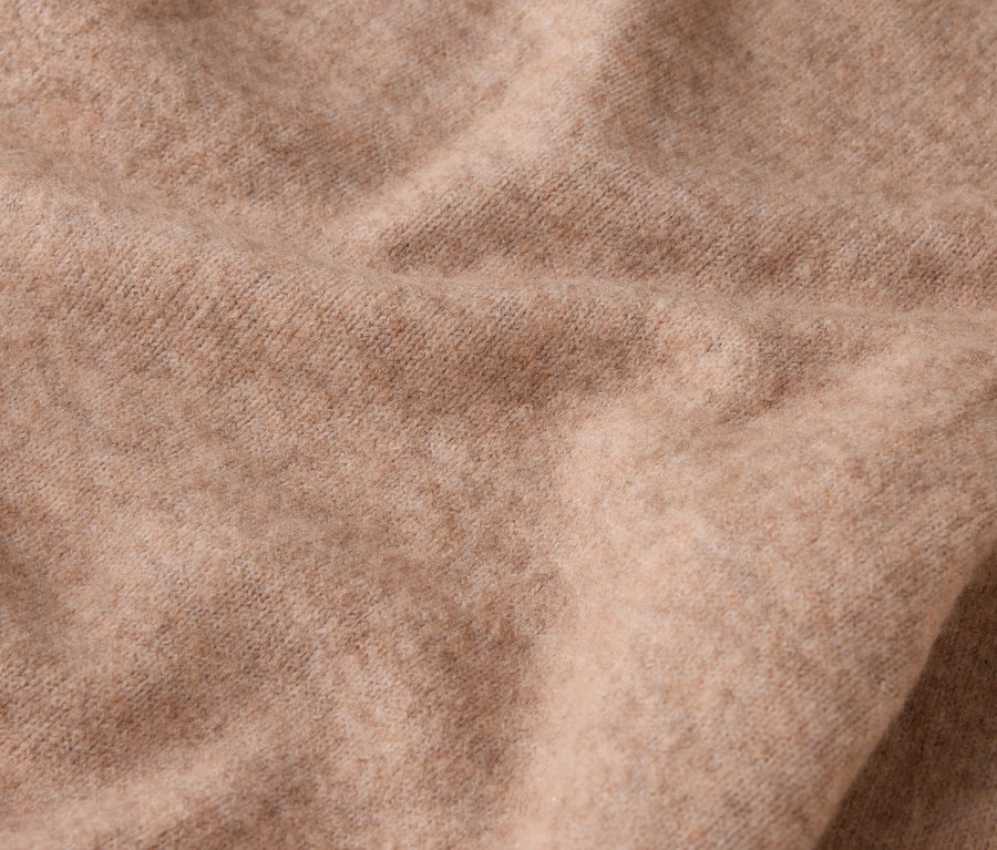 Nahaufnahme eines beigen Wollstoffes mit Falten.