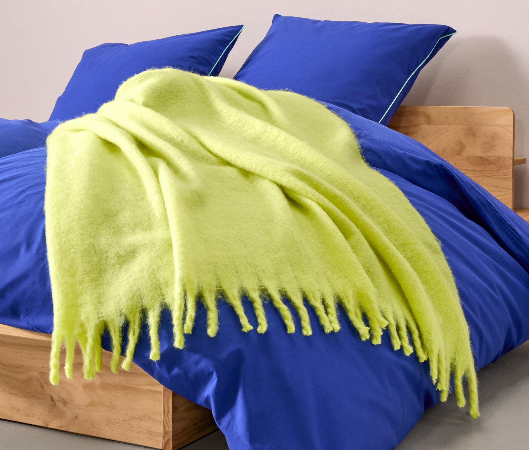 Gelbe Wohndecke, ca. 130 x 150 cm, liegt auf einem blauen Bett.