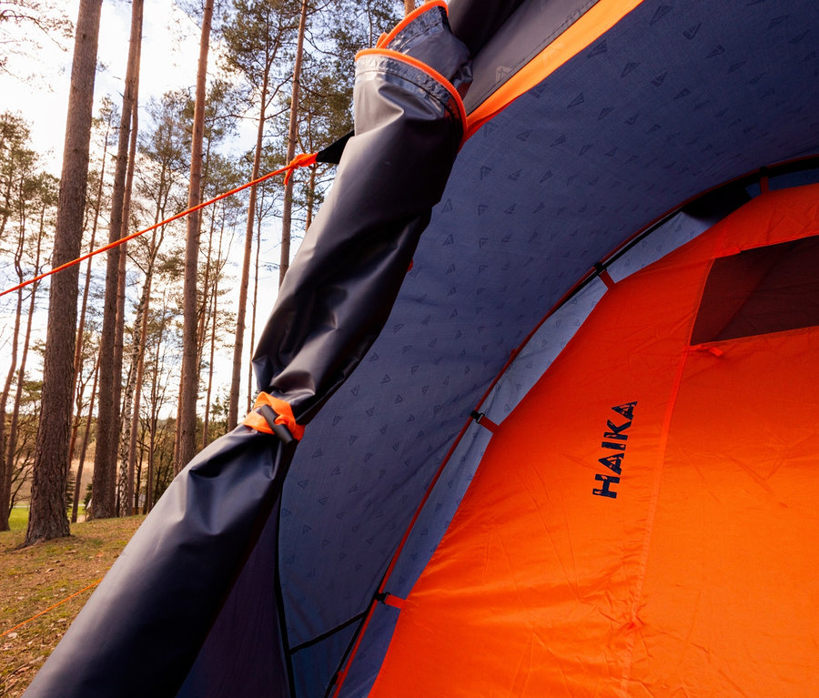 Innenansicht eines orangefarbenen Tambu Haika 3 Zeltes mit blauer Innenschicht in einem Wald.