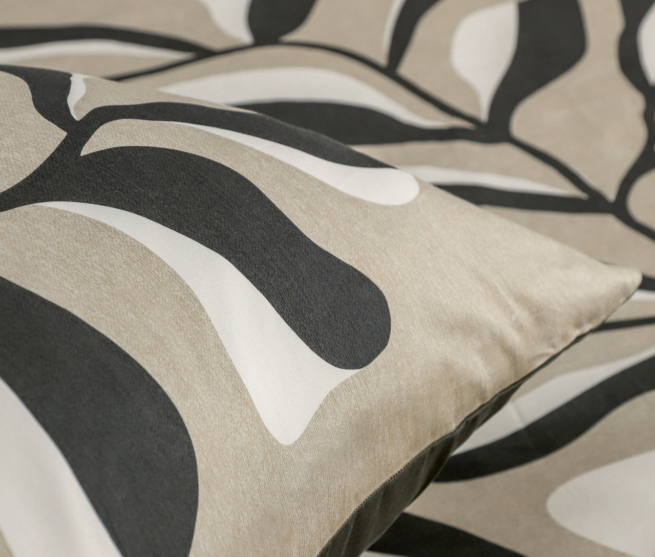 Detail eines Kissens mit abstraktem Muster in Beige, Weiß und Schwarz.